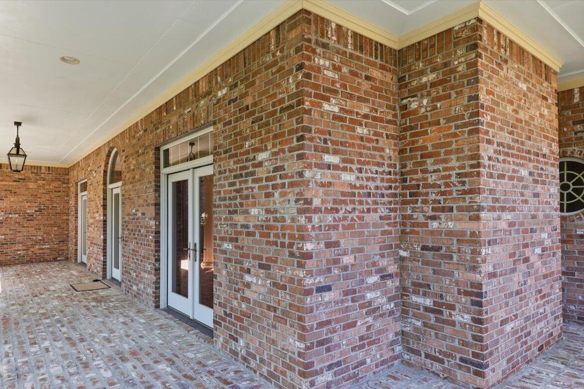 Wraparound brick front porch with brick floor and French doors