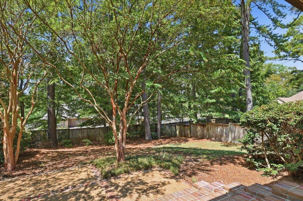 Landscaped backyard with crape myrtles and privacy fence