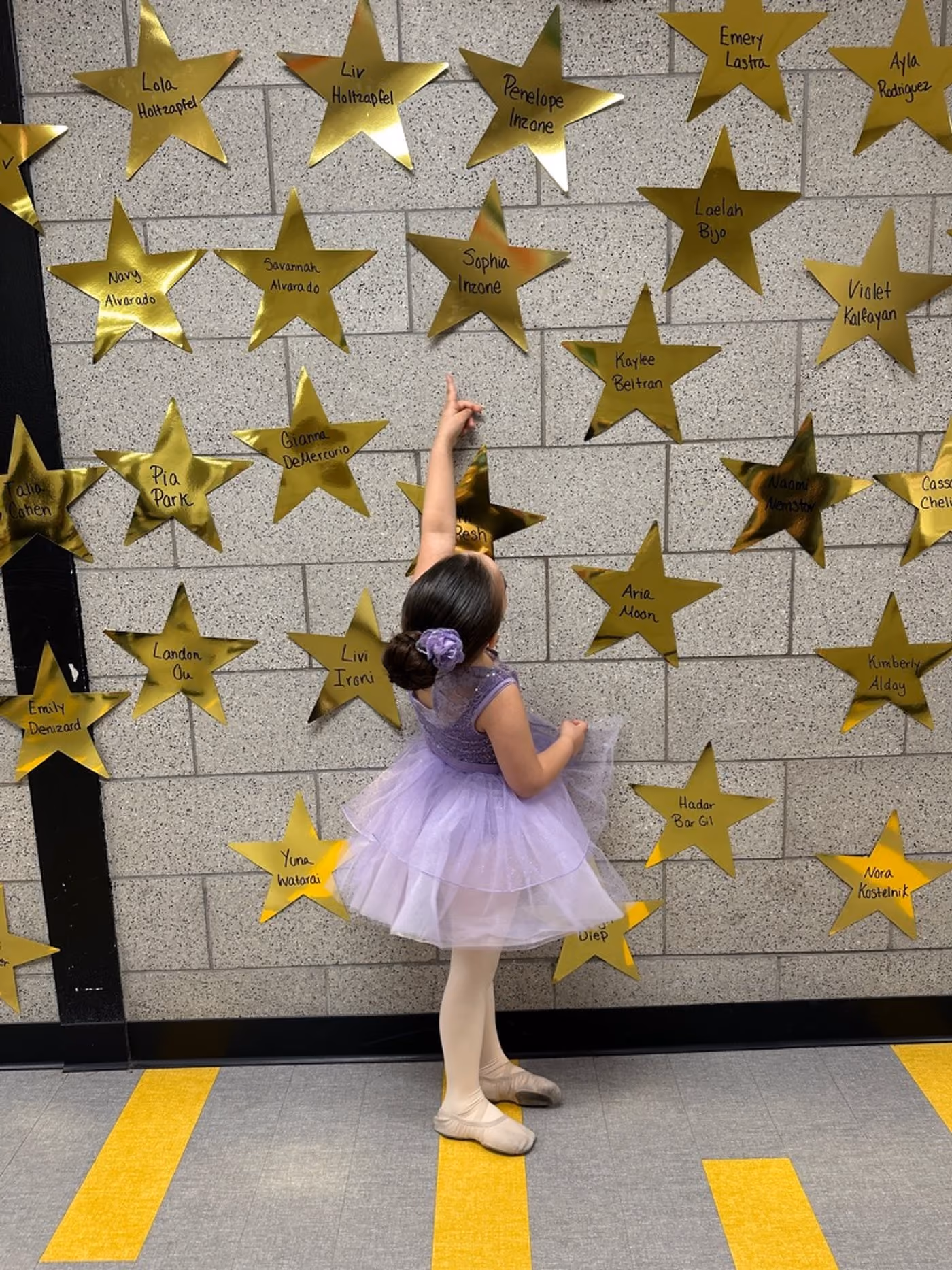 Young dancer reaching toward gold stars on the Revolution Dance Academy studio wall in Tenafly, NJ