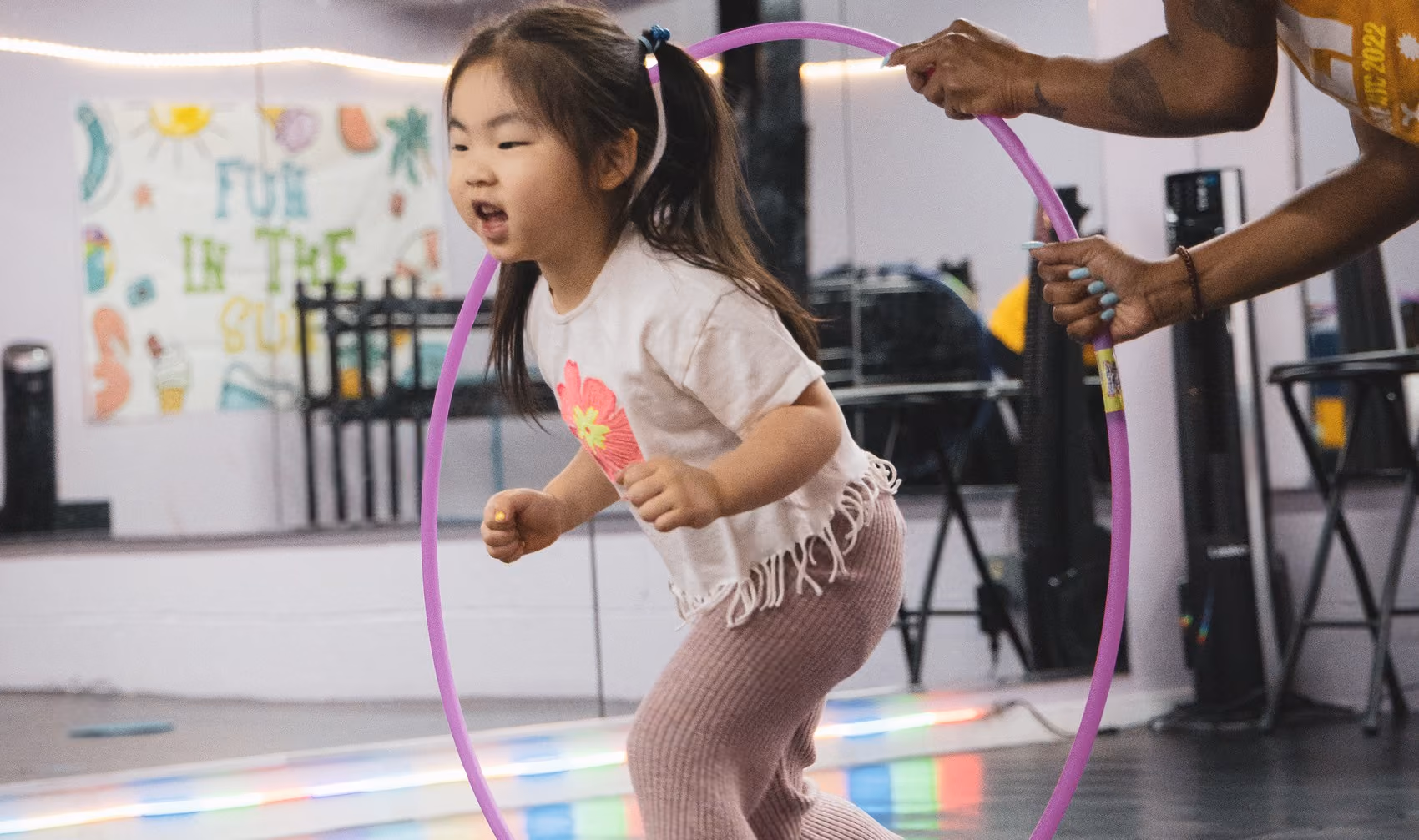 A young dancer jumping through a hoop held by her instructor during a private lesson at RDA