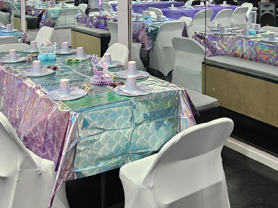 Mermaid-themed party table with iridescent tablecloth and place settings in the RDA studio