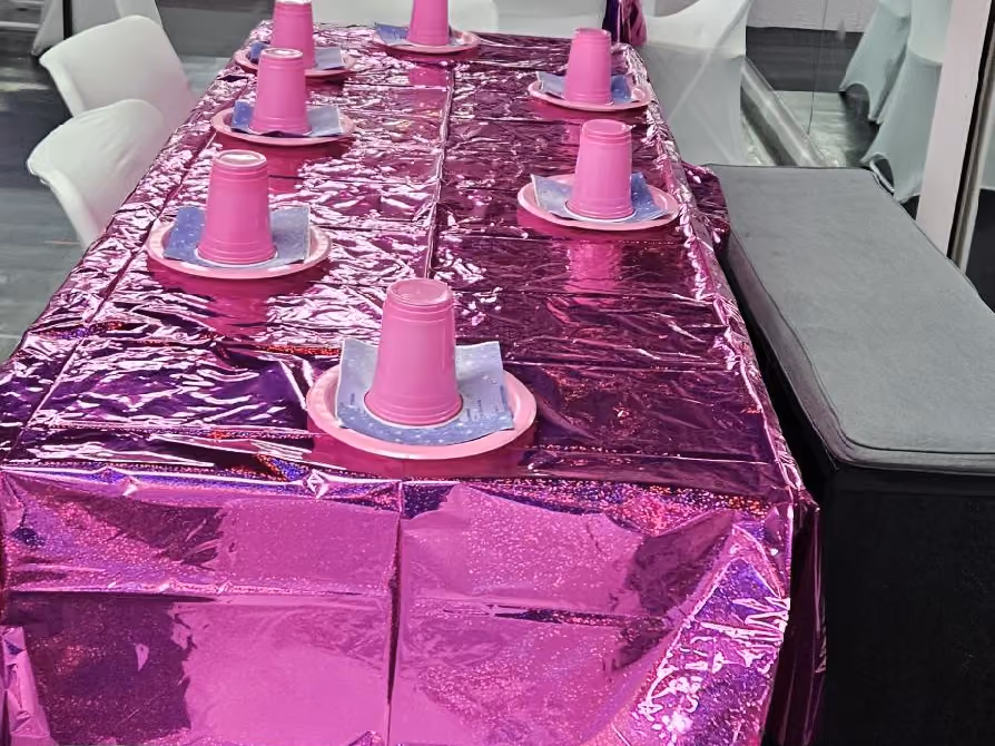 Pink foil-covered party table with cups and plates ready for guests at an RDA birthday party
