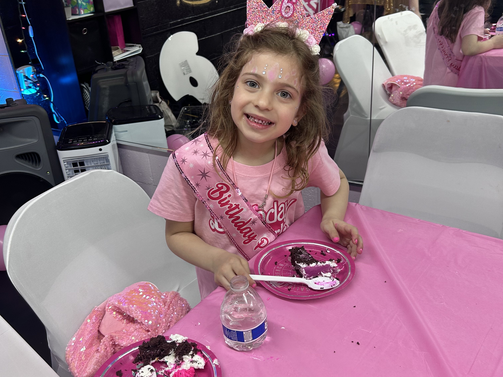 Smiling birthday girl in a pink crown and sash eating cake at her RDA studio party