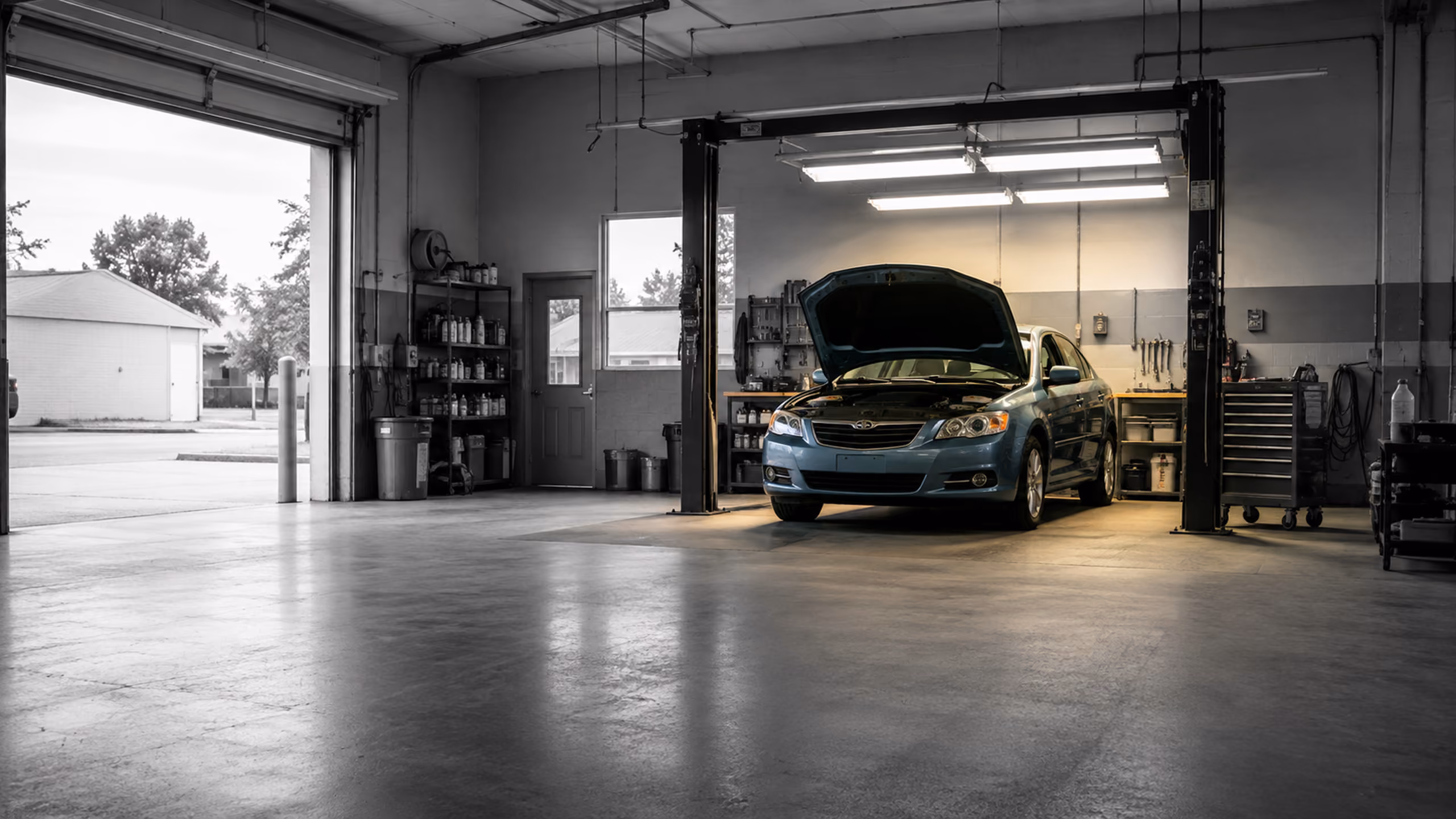 Independent auto repair shop with a vehicle illuminated inside the service bay.