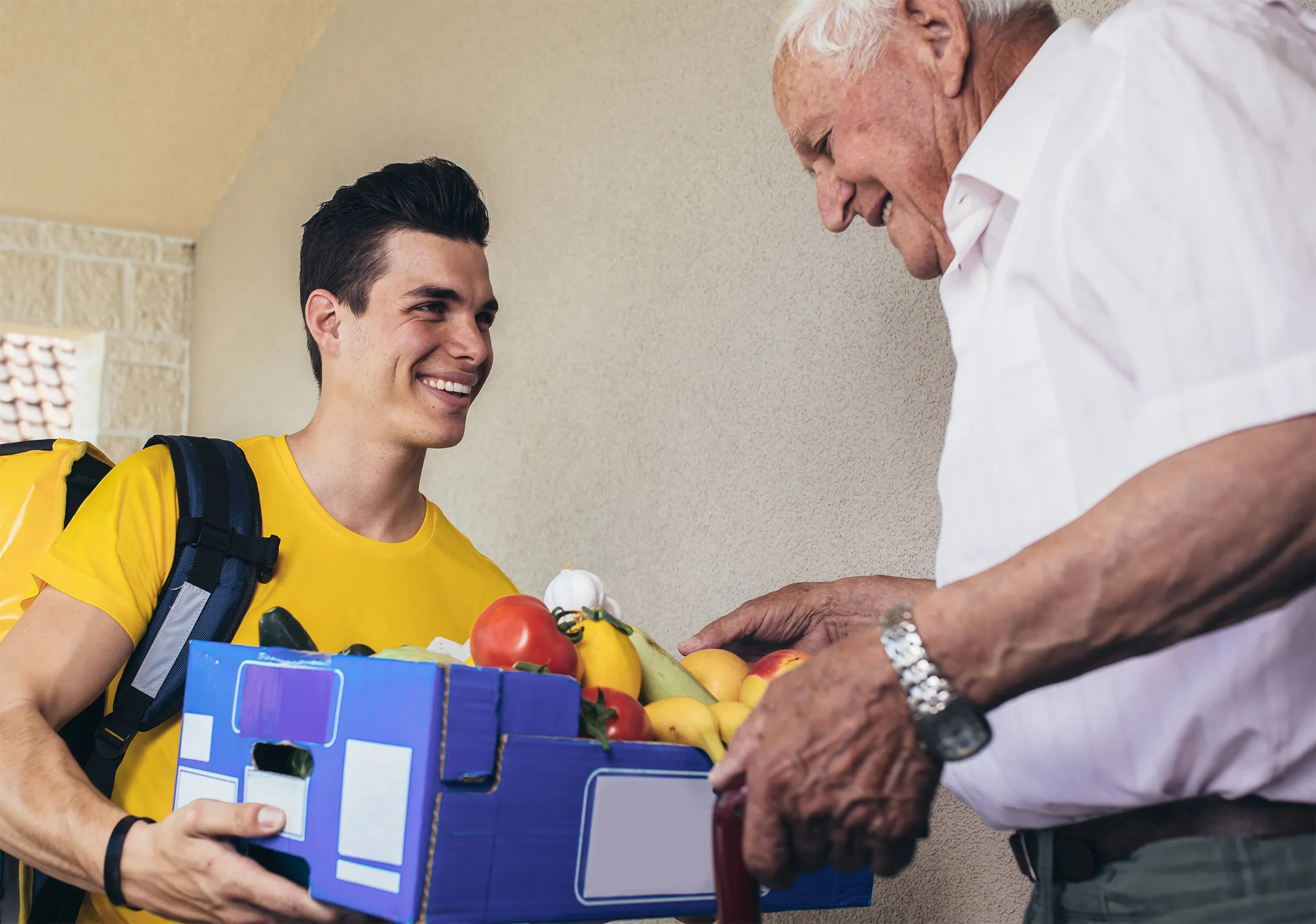 Volunteer handing groceries to an elderly man