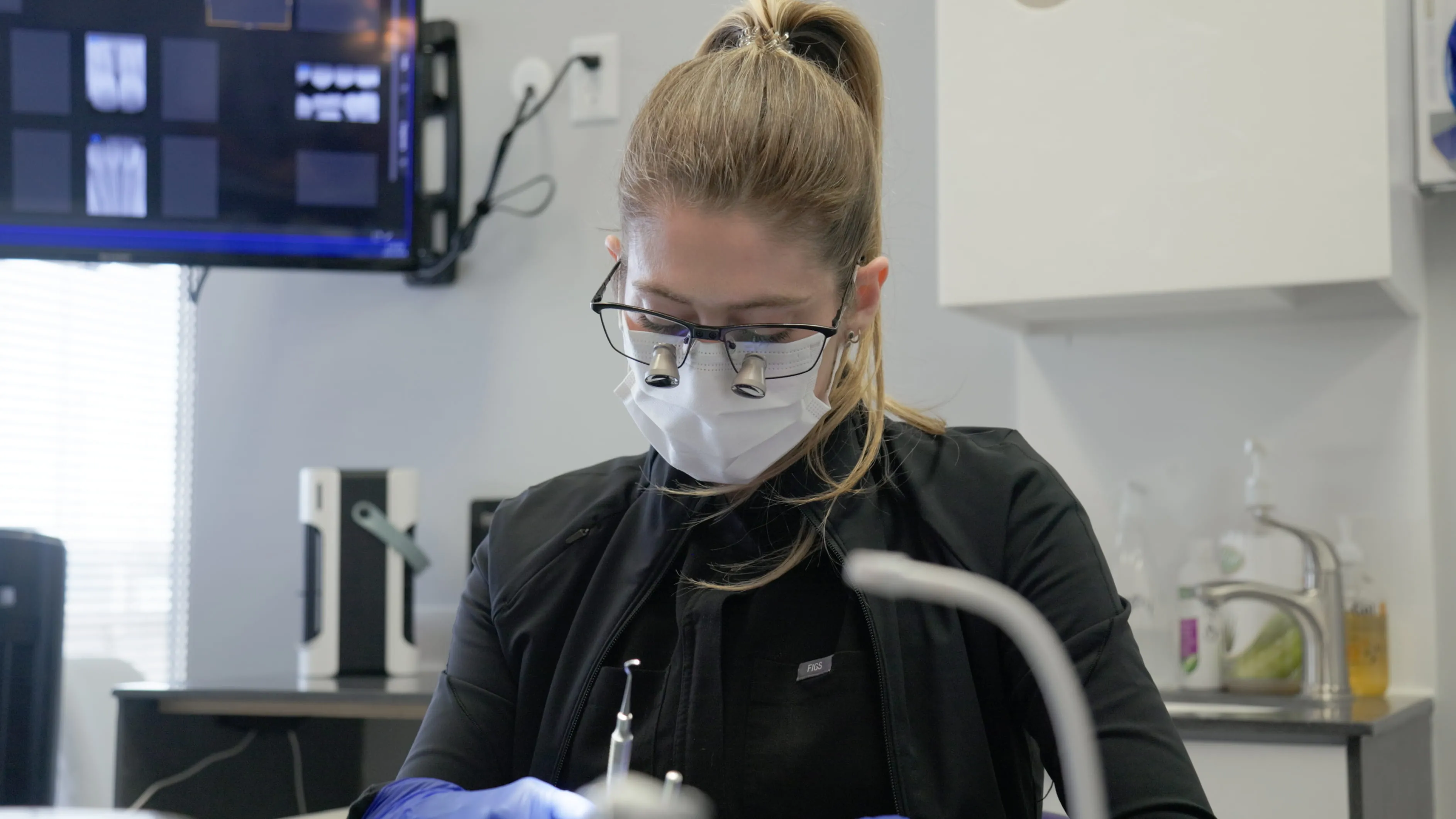 Dental hygienist wearing magnifying loupes during a cleaning in SE Calgary