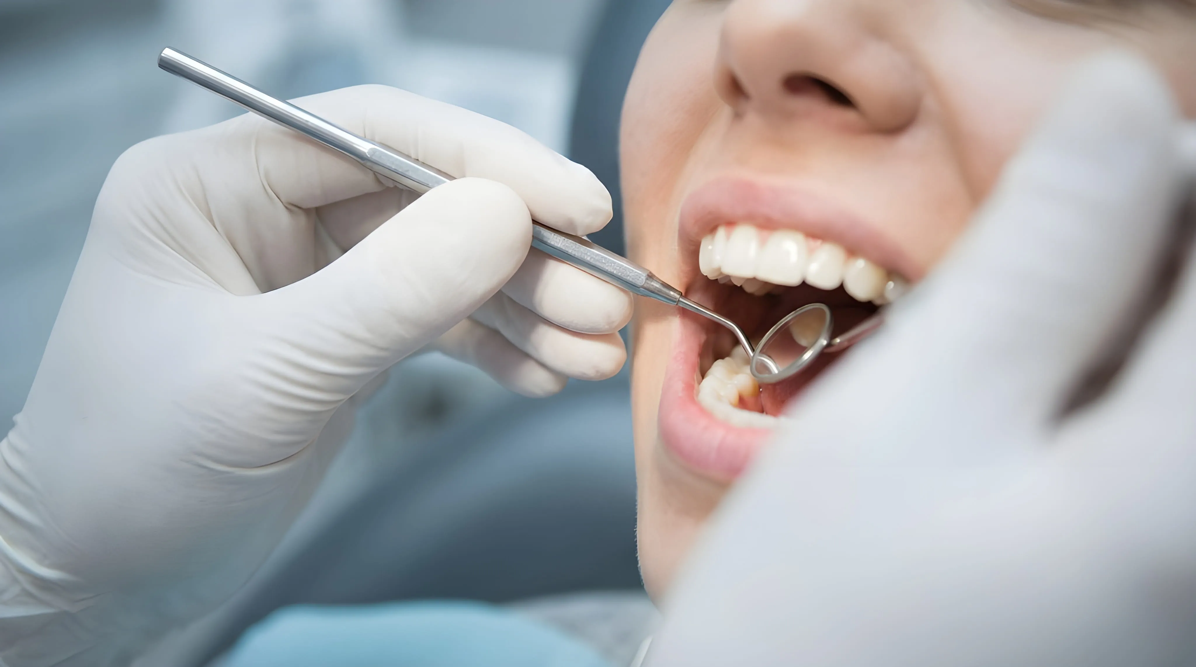 Dentist checking a patient's teeth with a mirror during an exam