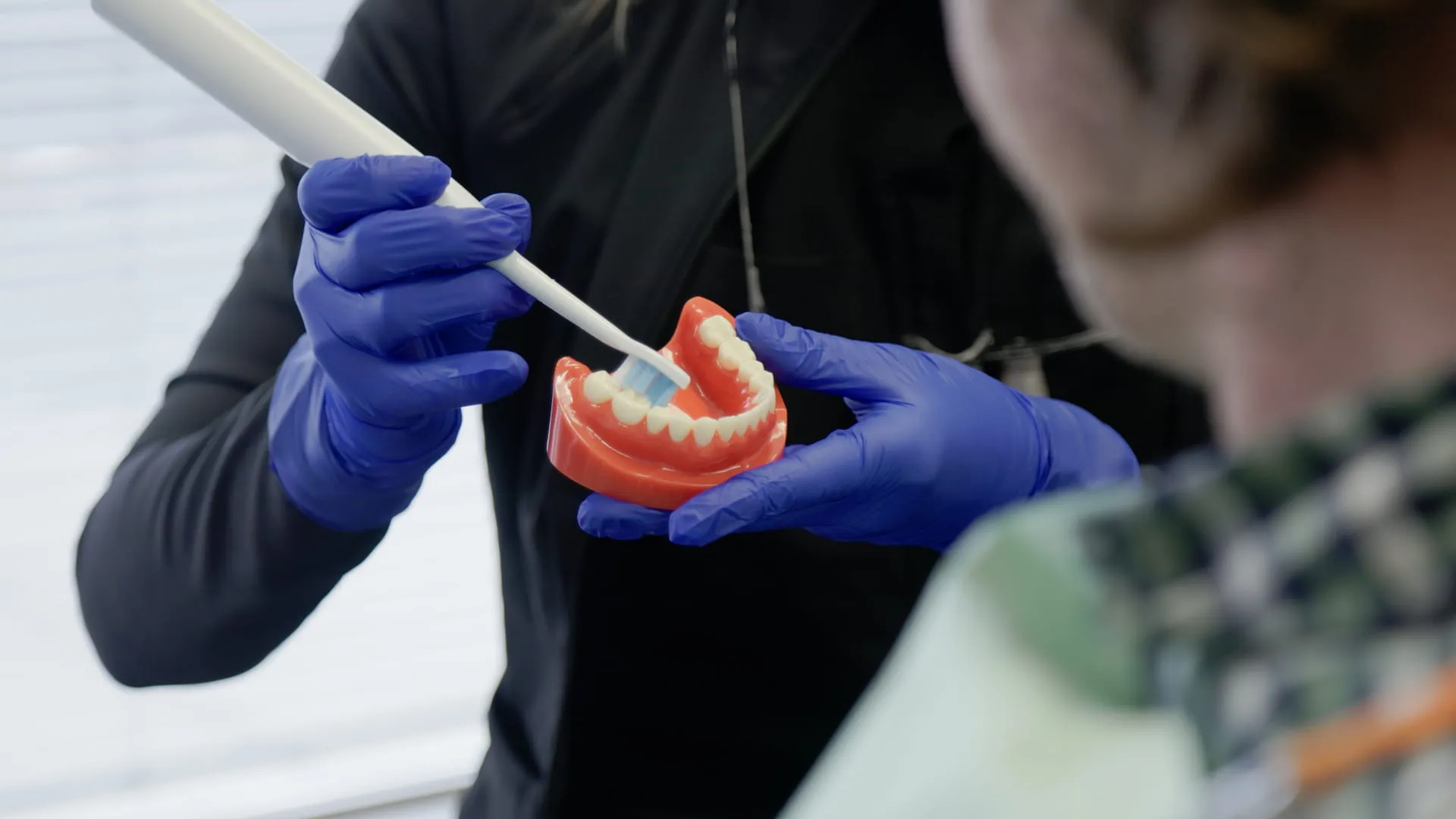 Team member showing a patient brushing technique on a model at Macleod Trail Dental