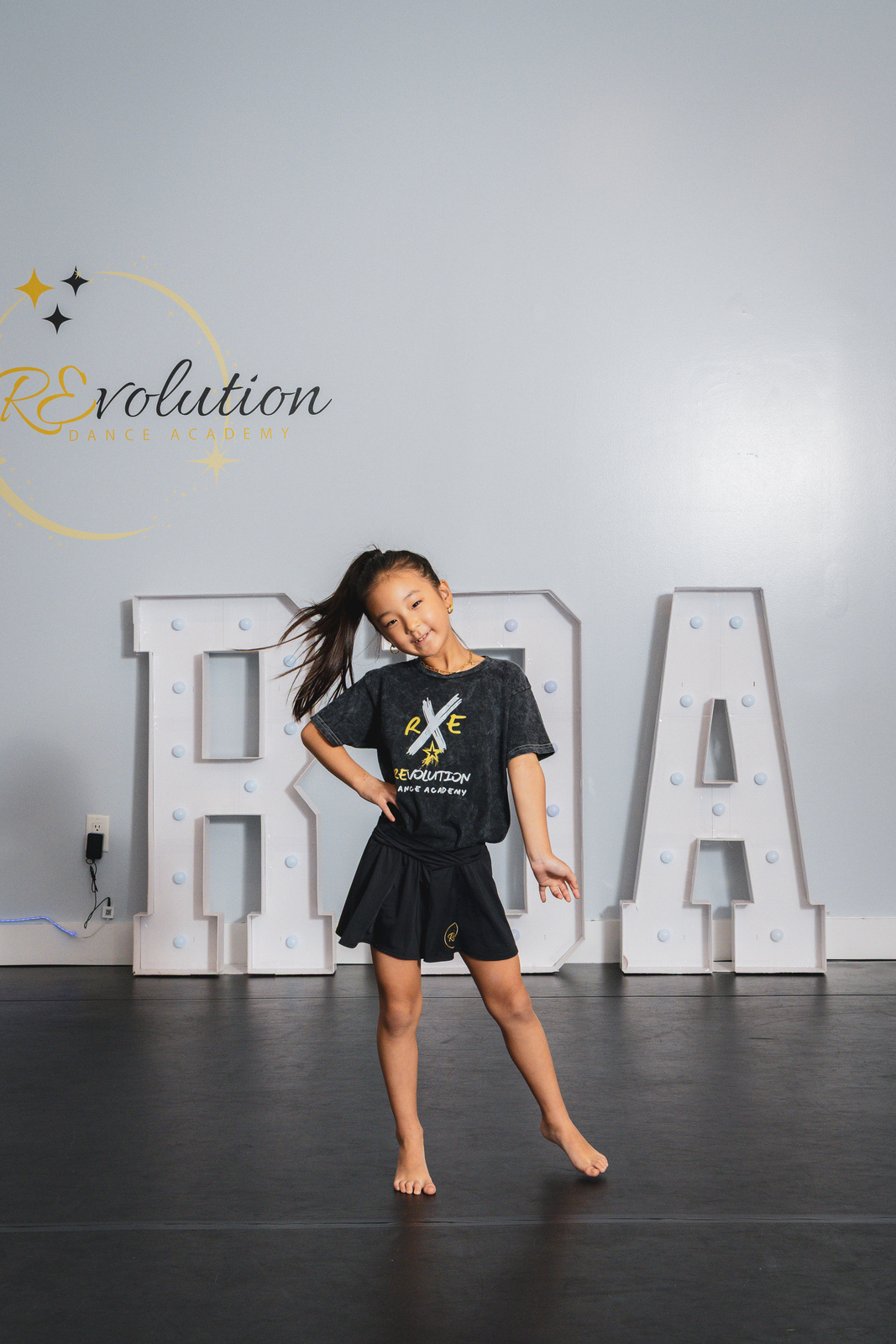 A jazz dancer mid-jump in front of the RDA marquee letters