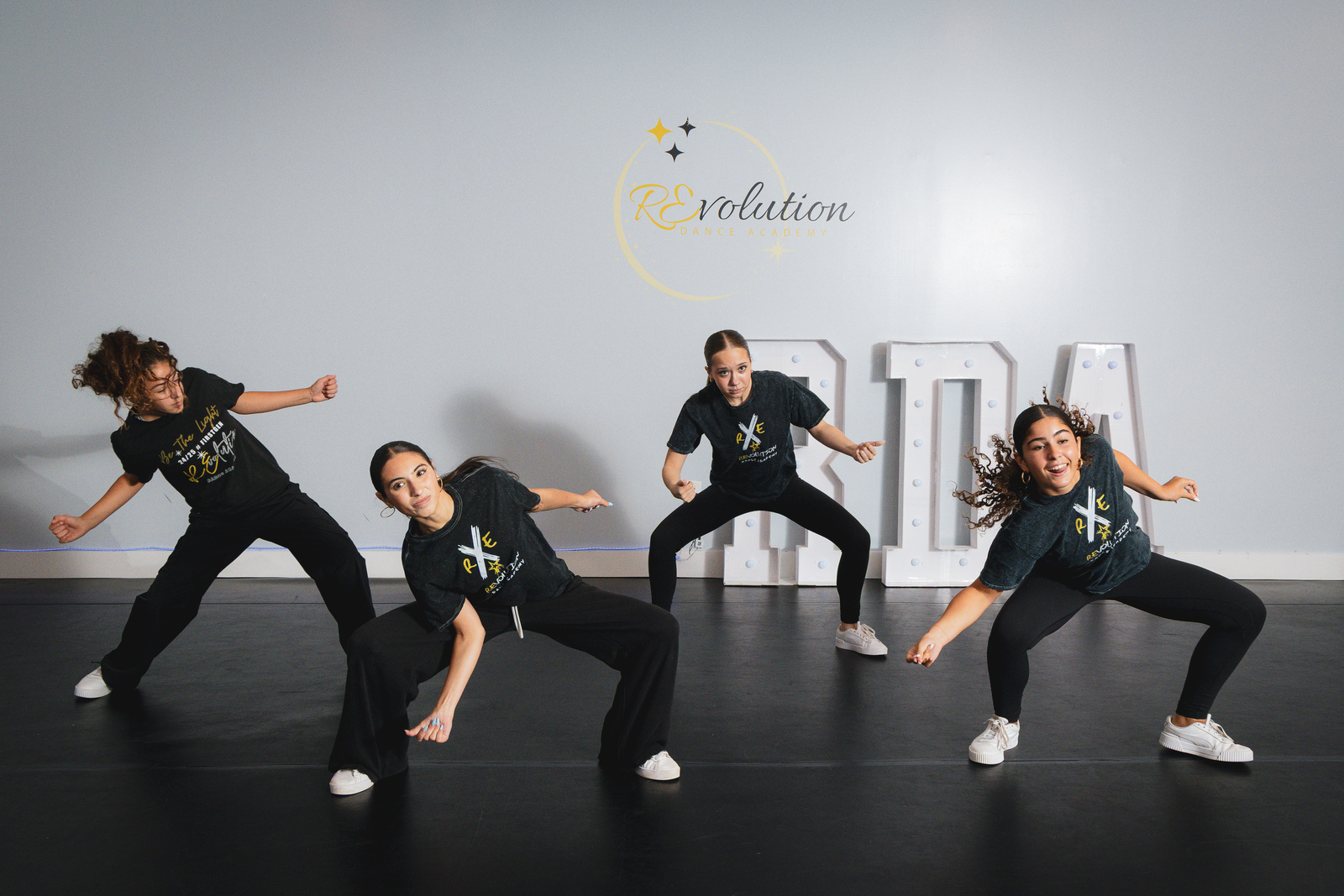 Hip hop dancers hitting a low pose together at Revolution Dance Academy