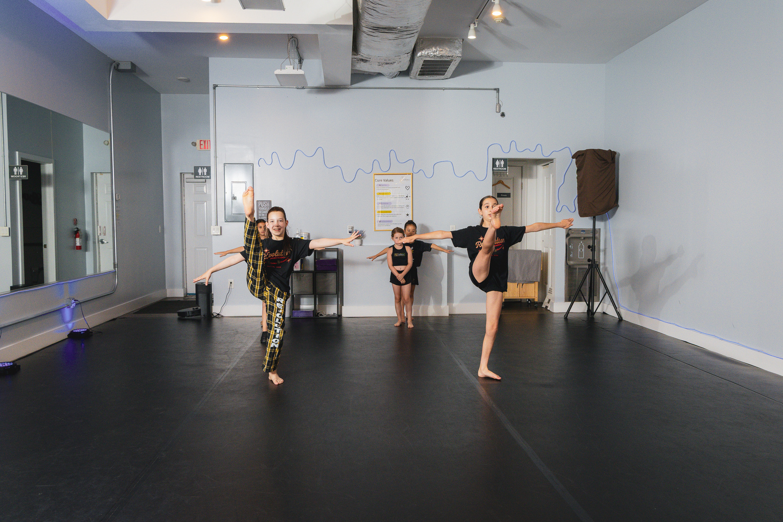 Jazz dancers leaping across the studio at Revolution Dance Academy