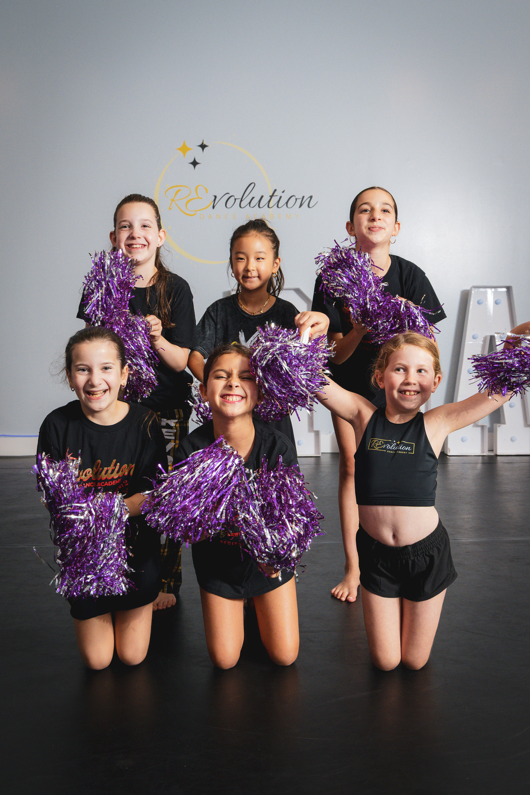 Cheerfunk dancers jumping with pom-poms at Revolution Dance Academy