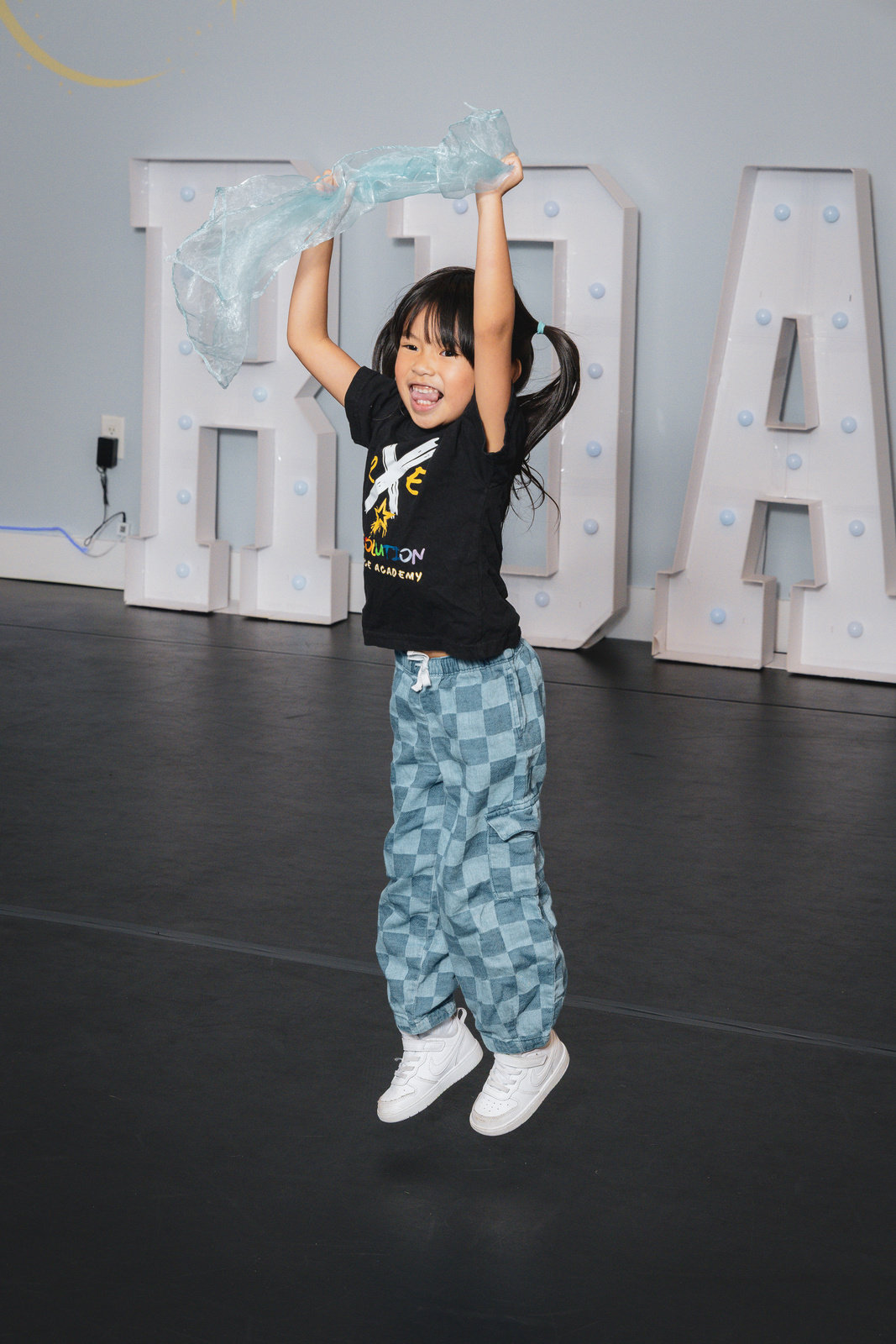 A preschool dancer jumping with a scarf at Revolution Dance Academy