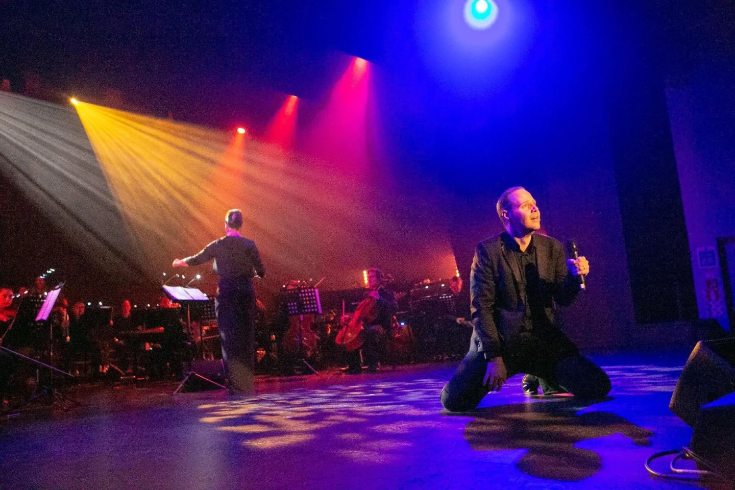 Scot Hall performing onstage with a conductor and orchestra.