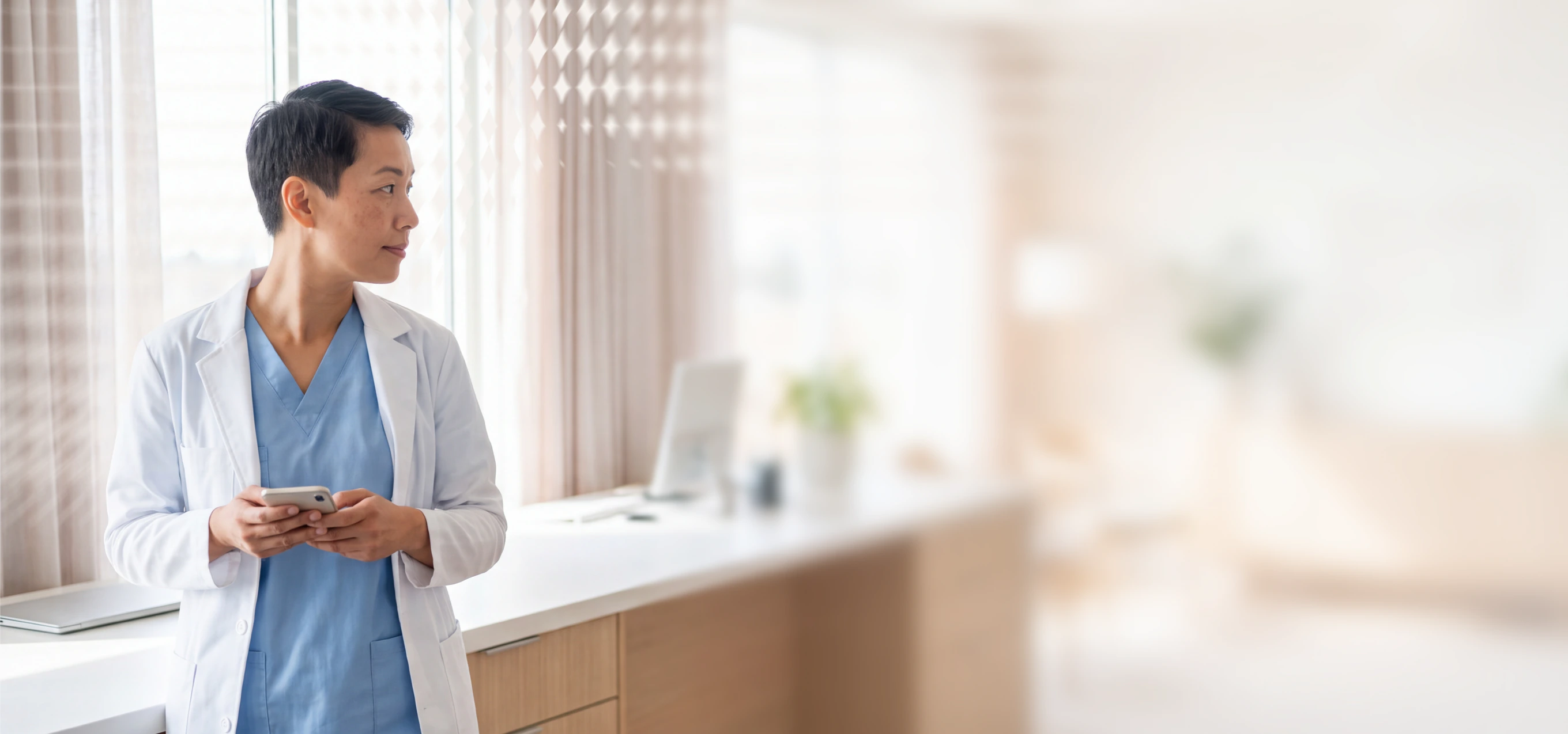 Doctor in white coat using phone in office setting