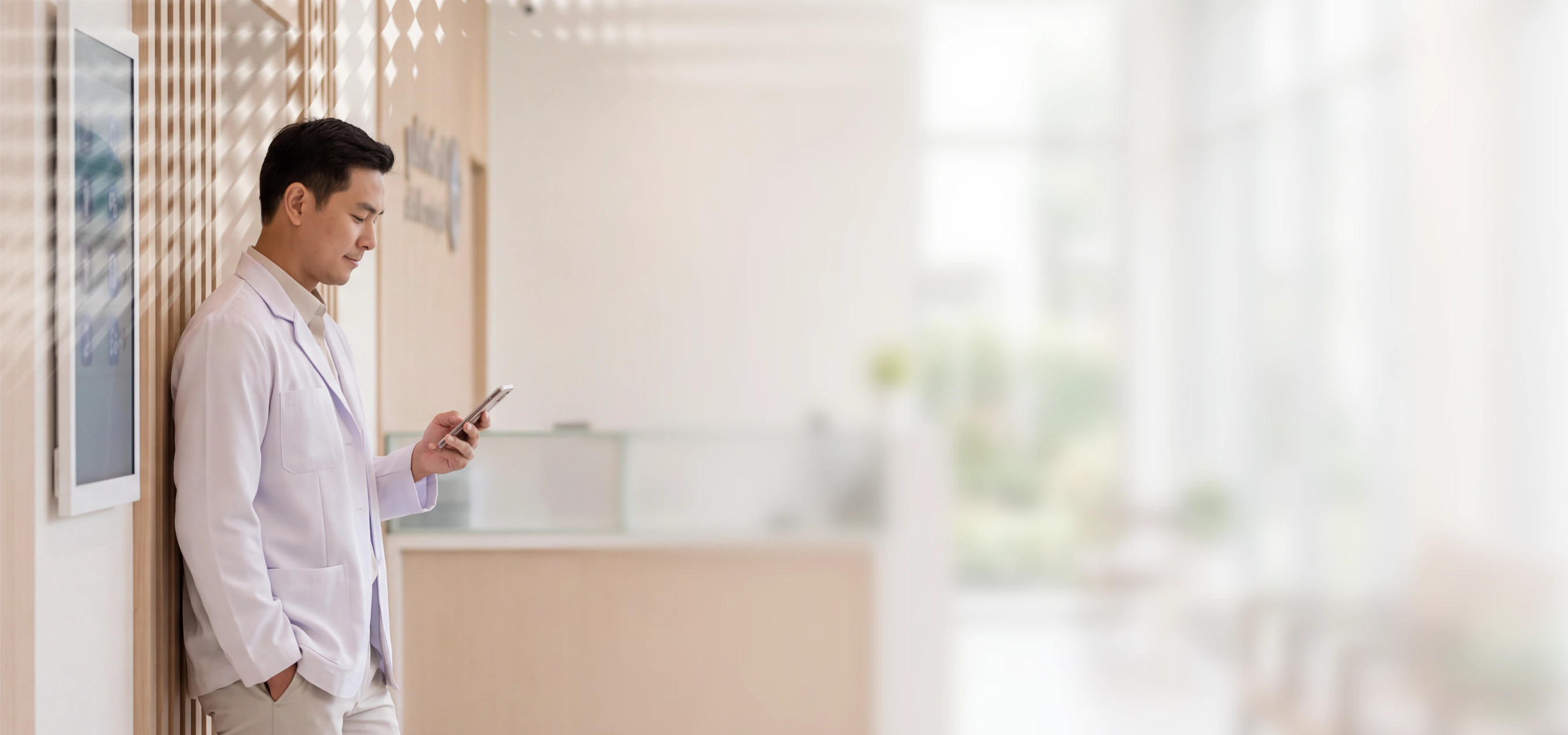 Doctor in white coat using phone in modern clinic setting