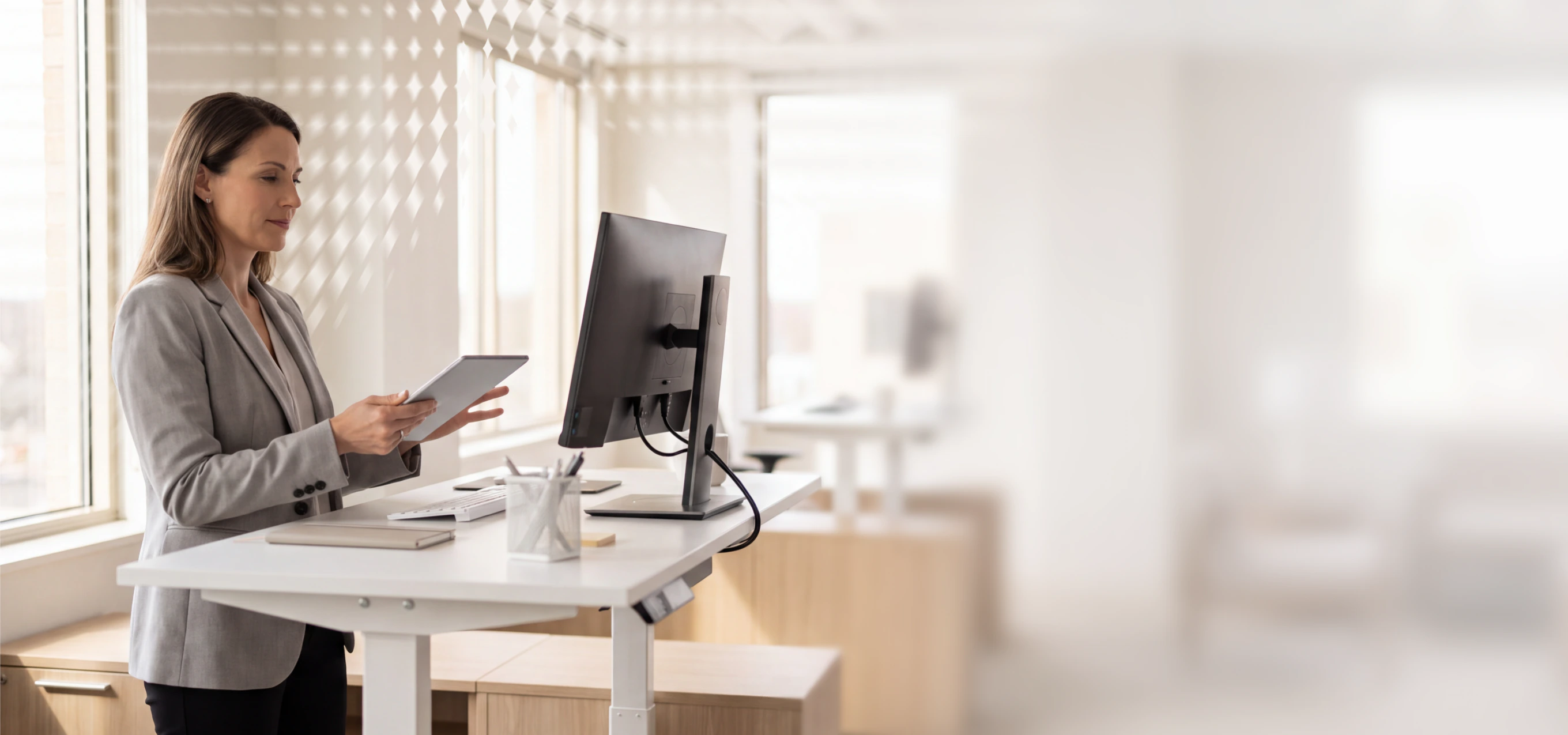 Woman using a tablet at a standing desk in a bright office