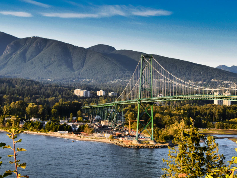 A scenic view of the Lions Gate Bridge in Vancouver, with mountains in the background and a body of water in the foreground