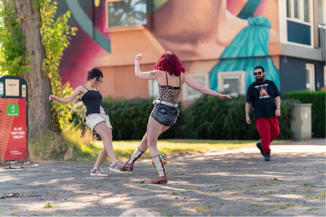 Twee jongeren dansen op straat voor een groot kleurrijk muurschildering in Leeuwarden.