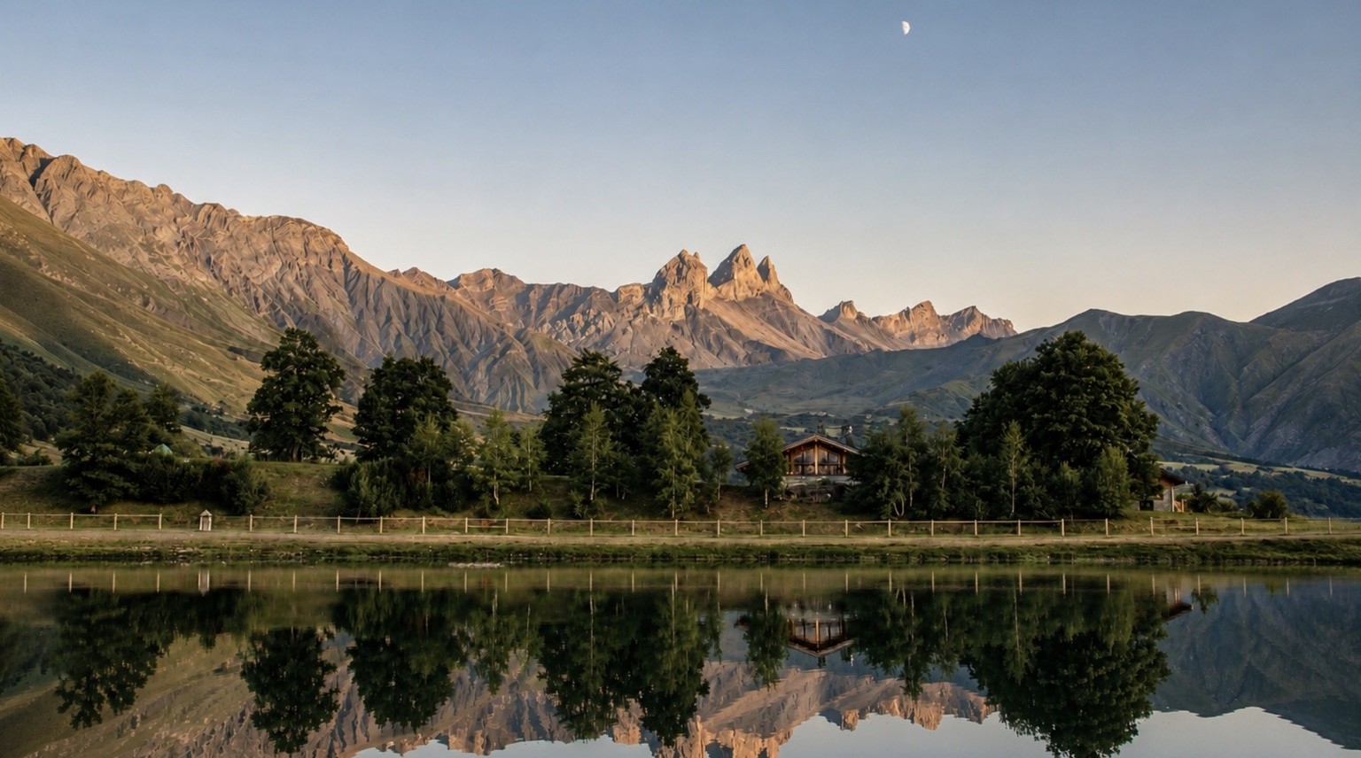 Les Aiguilles d’Arves au-dessus d’un chalet et d’un plan d’eau, à Albiez-Montrond