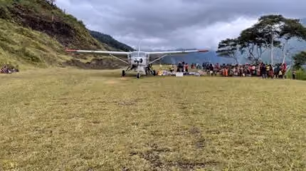 A small plane landing on a grassy field in Papua, Indonesia.