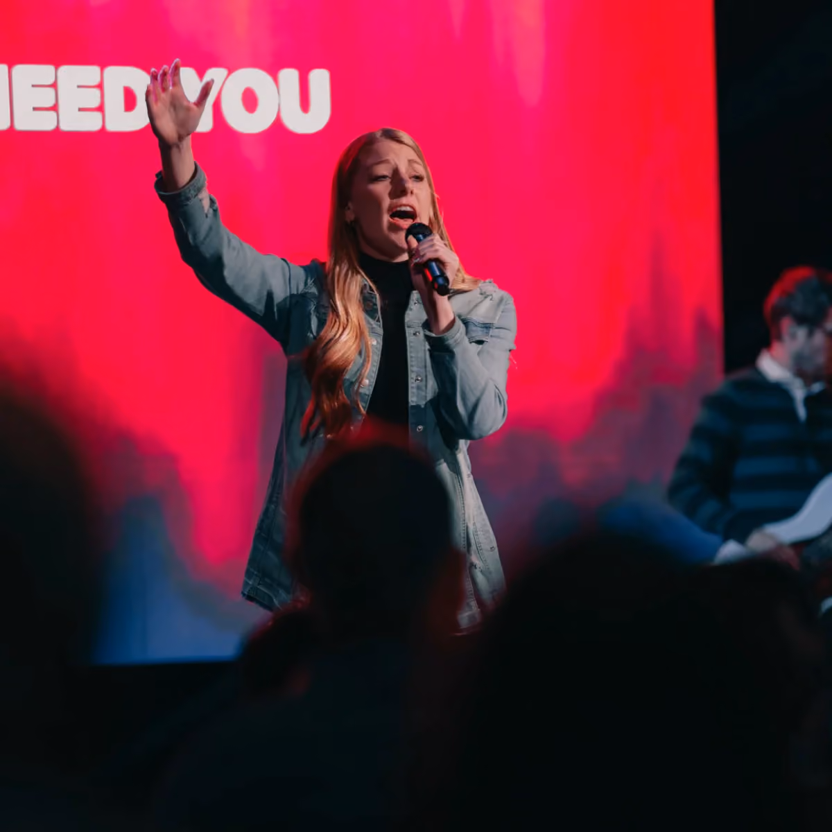 A woman singing on stage during worship at Northshore Church.