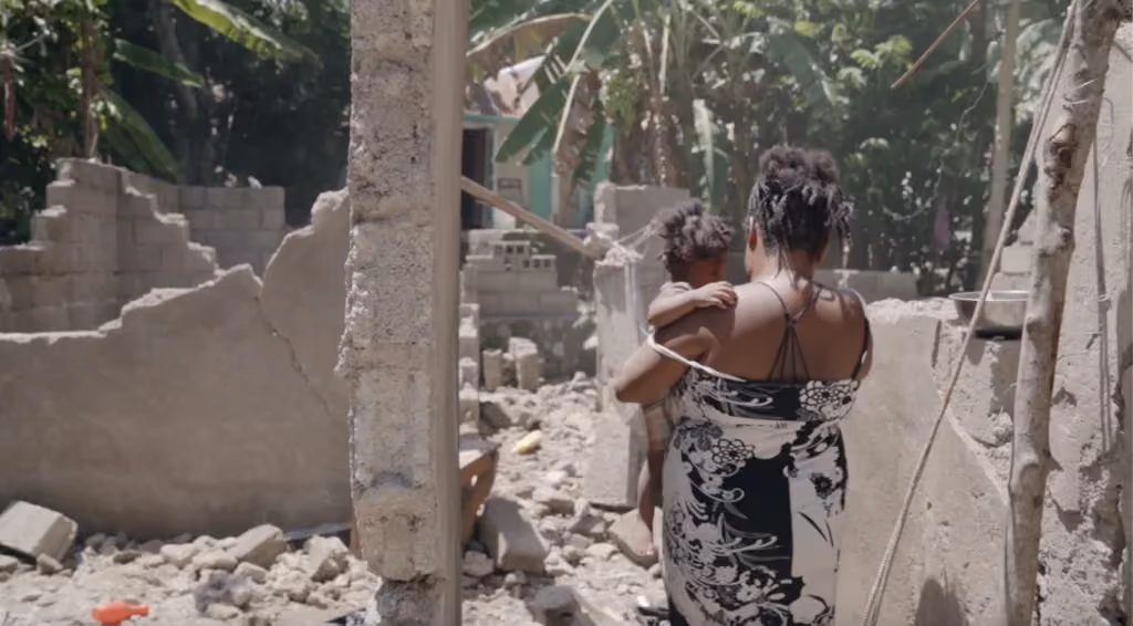 A woman holding a child amid earthquake debris in Haiti.