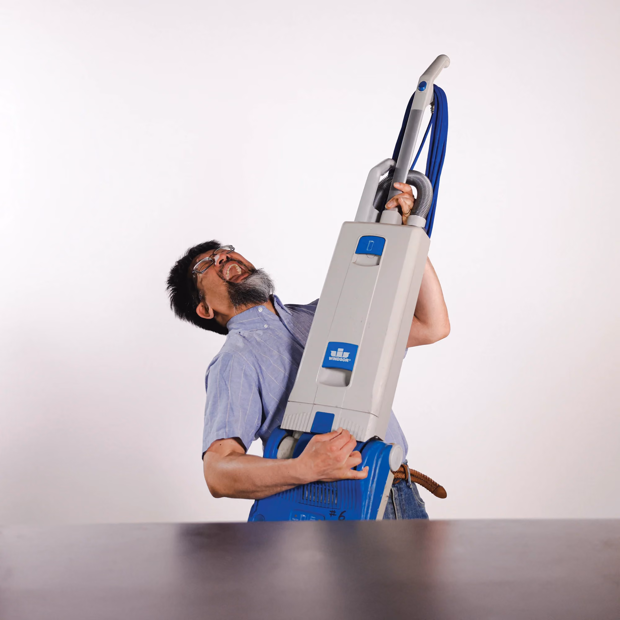 K-Y Su holding a vacuum cleaner, reflecting his work in facilities support.