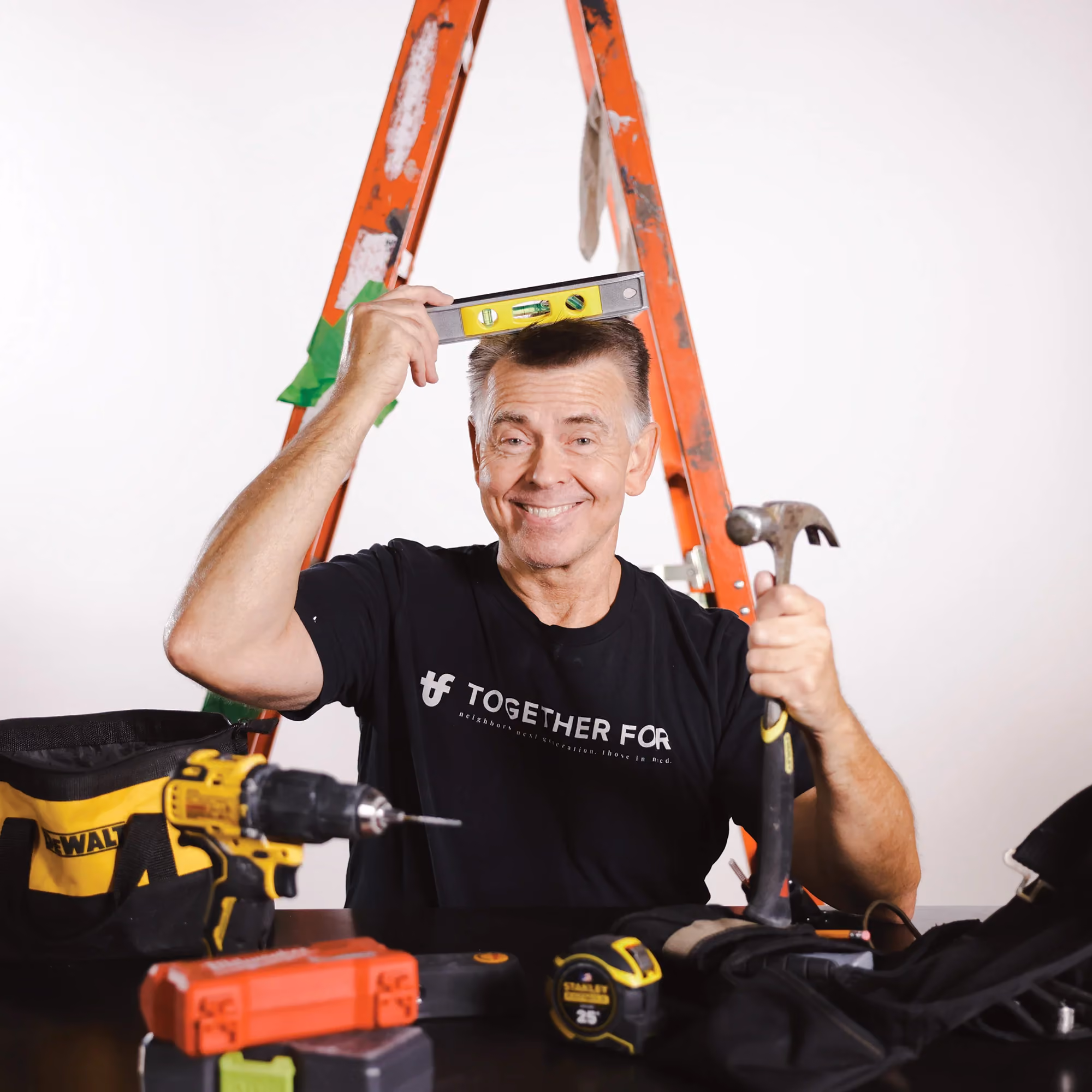 Pete Lindquist holding tools by a ladder, reflecting his work in maintenance.