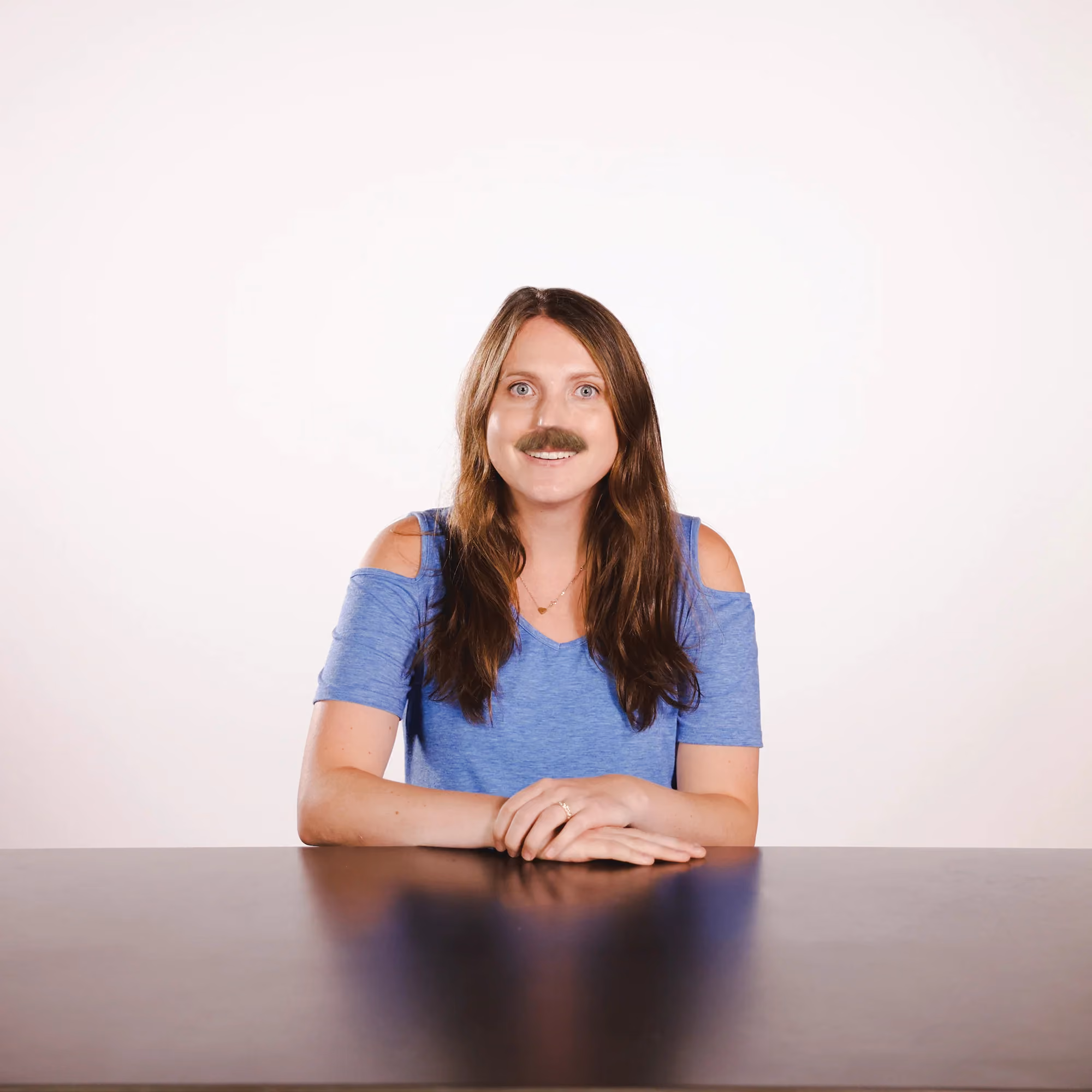 Kelly Cutler wearing a fake mustache in a lighthearted staff photo.