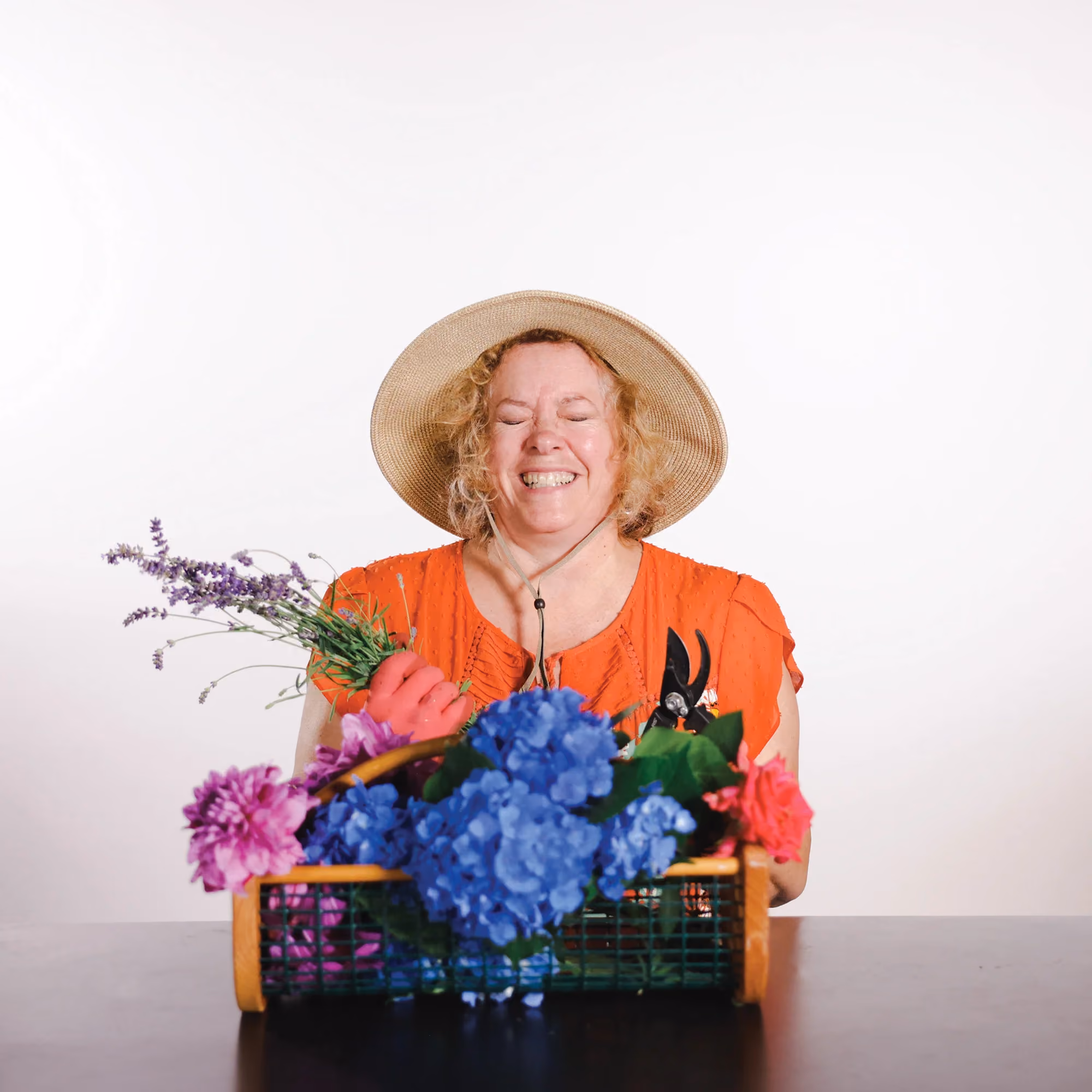 Kathy F holding flowers and wearing a hat in a candid staff photo.