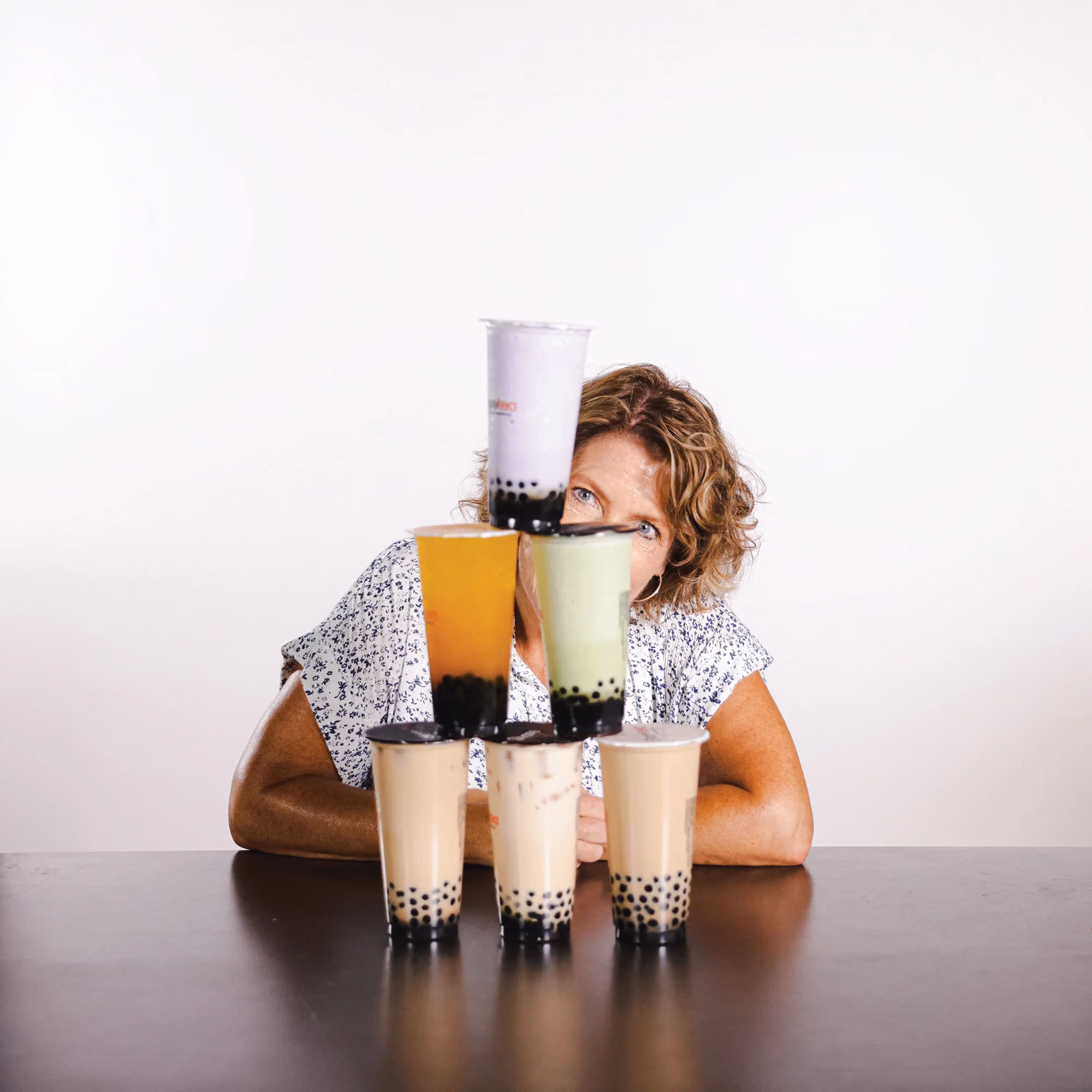 Carry M hiding behind bubble tea cups in a lighthearted staff photo.