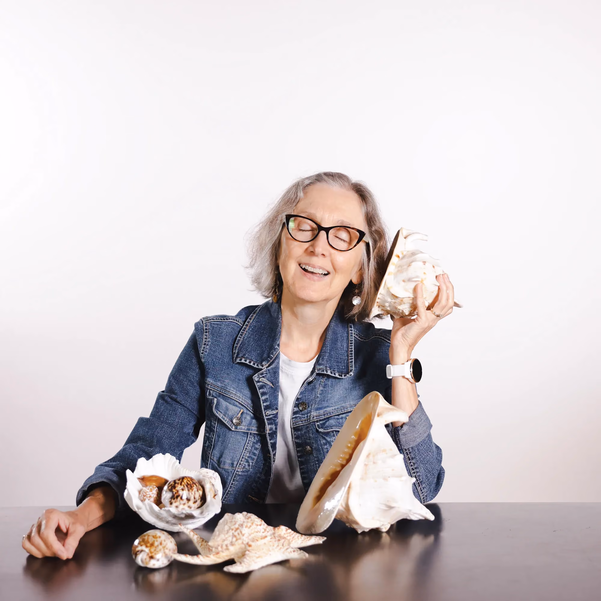 Teri Hamilton smiling while holding a seashell in a candid staff photo.