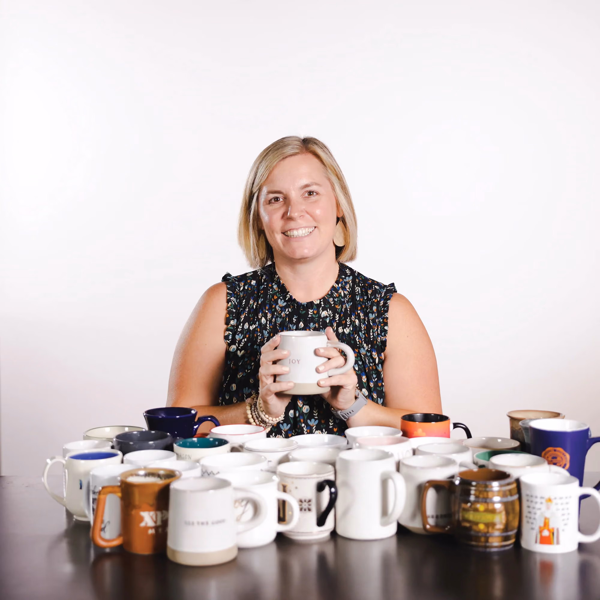 Jackie Giardino holding a mug surrounded by mugs in a candid staff photo.