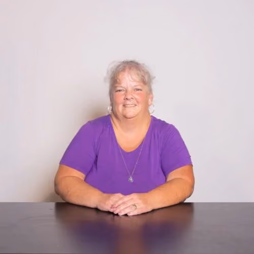 Linda Smith, Childcare Associate at Northshore Church, sitting in a purple shirt.