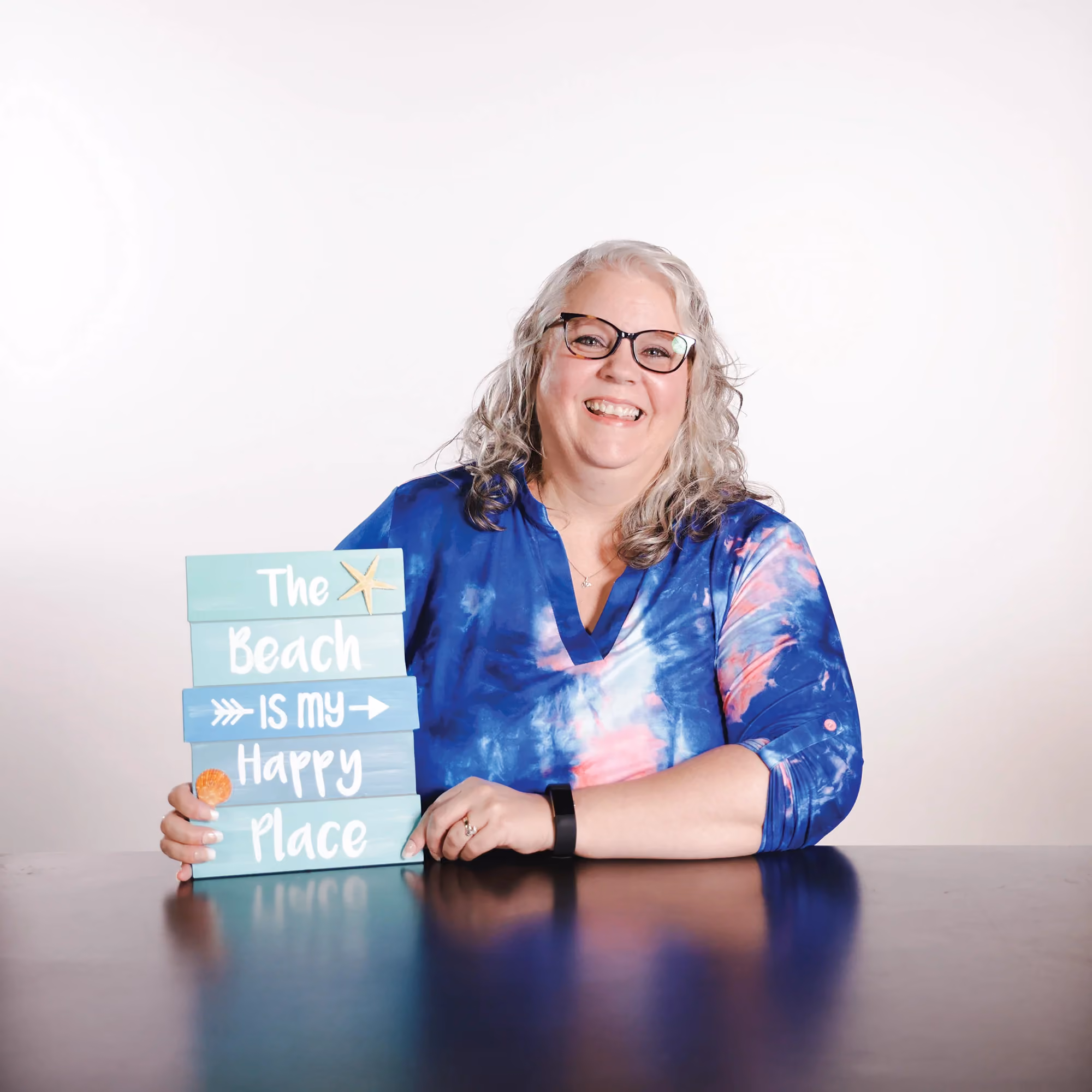 Ginny Roos holding a beach sign in a candid staff photo.