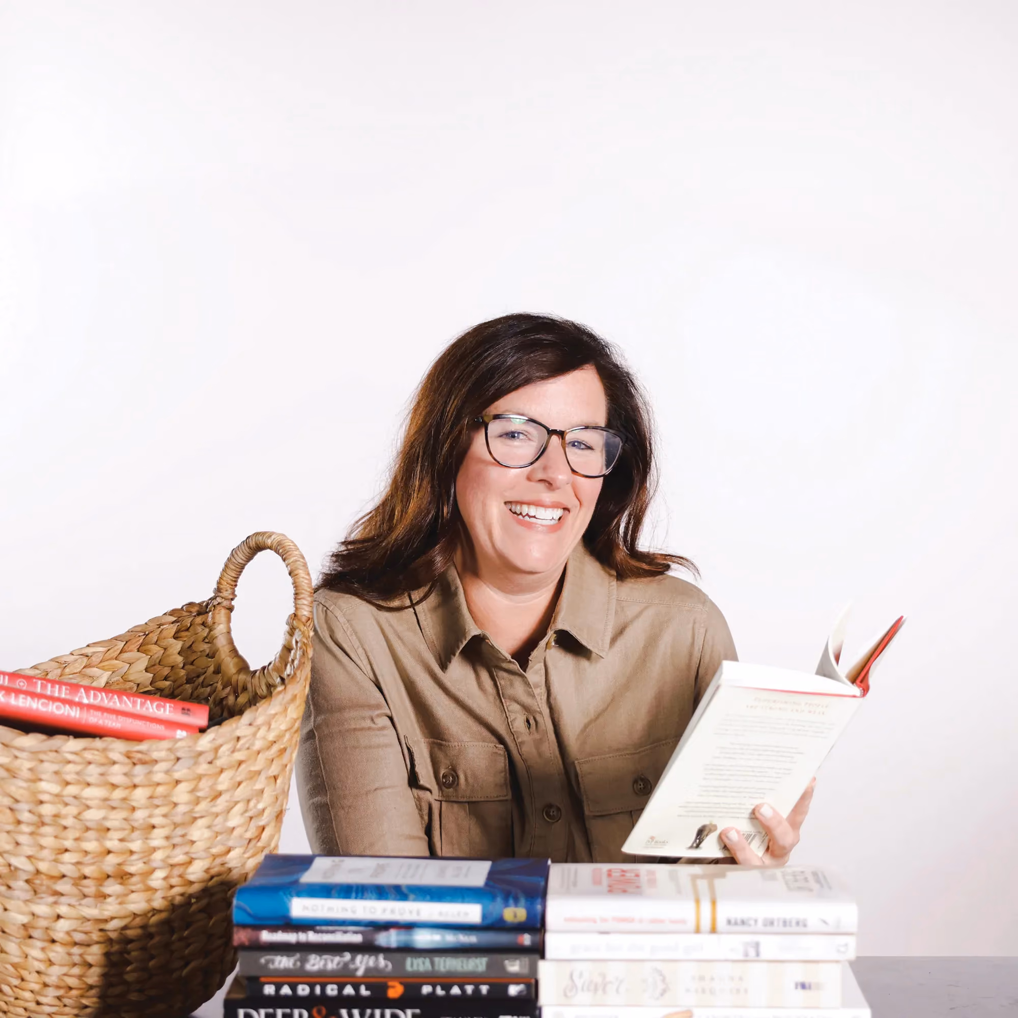 Lauren Neal smiling while reading books in a candid staff photo.