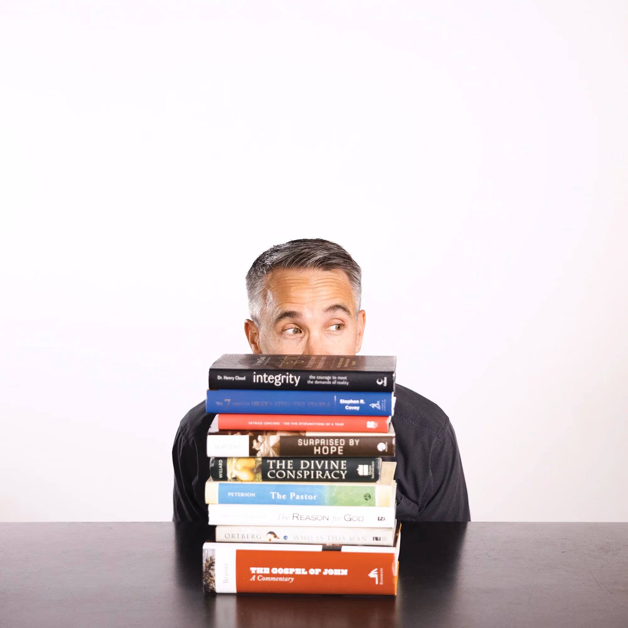 Scott Scruggs hiding behind a stack of books in a candid staff photo.