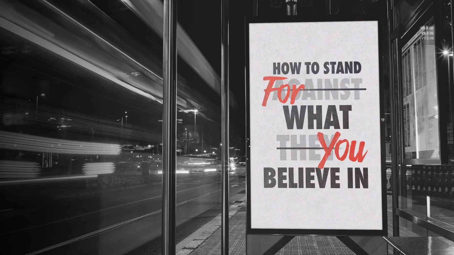 Black and white urban scene with a sign reading 'How to stand against what they believe in' with red crossed out words.