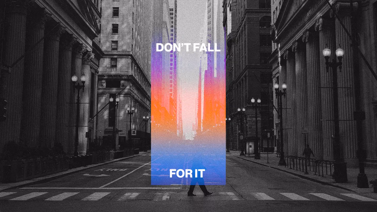 Black and white city street with colorful vertical banner reading 'DON'T FALL FOR IT' and a person walking across crosswalk.