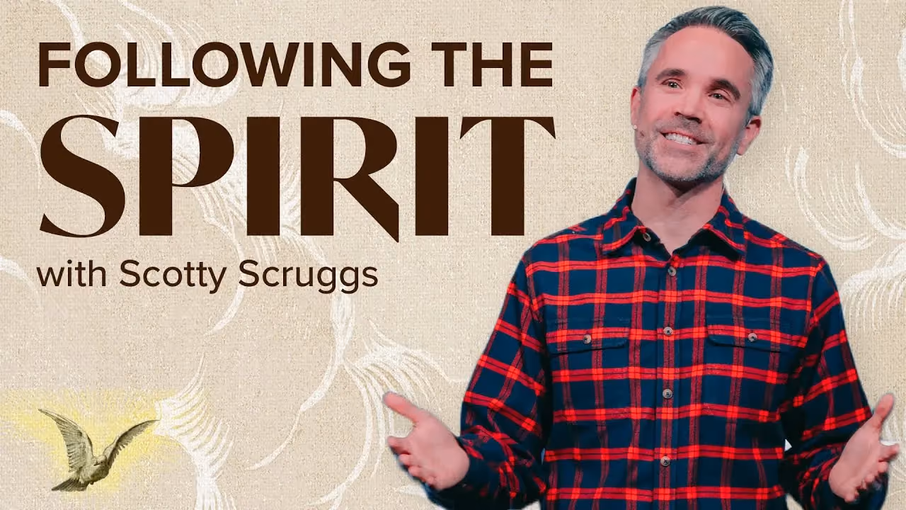 Man in red and blue plaid shirt smiling with open hands against a textured background with text and bird illustration.