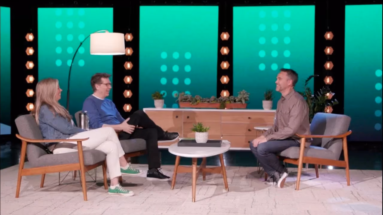 Three people seated on a set with green background and plants.