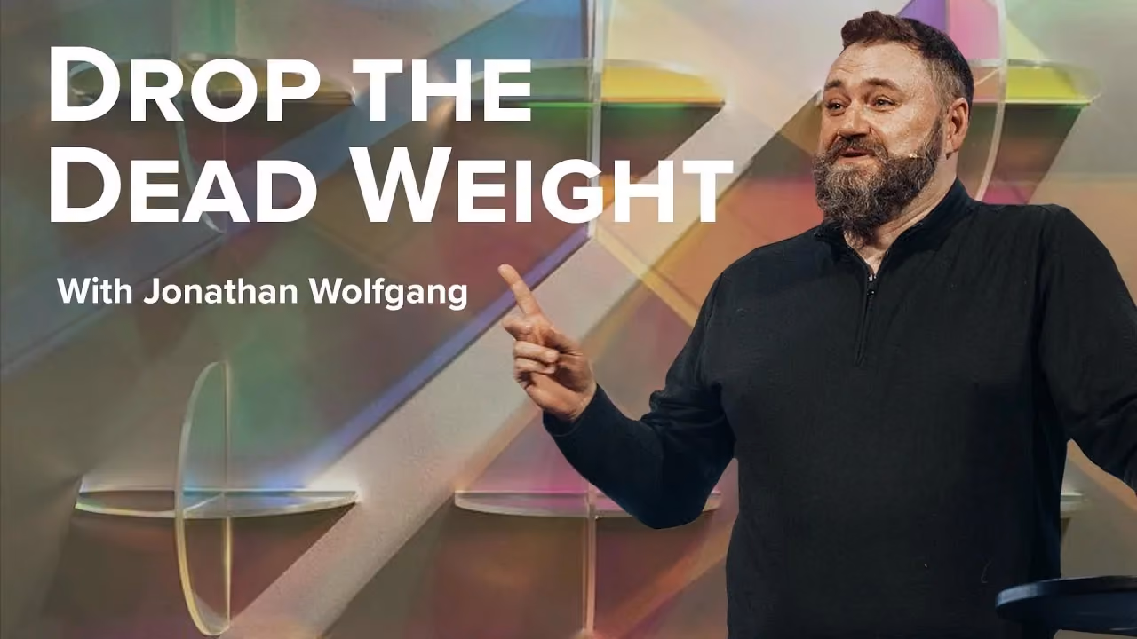 Drop the Dead Weight with Jonathan Wolfgang, pointing beside iridescent glass panels.