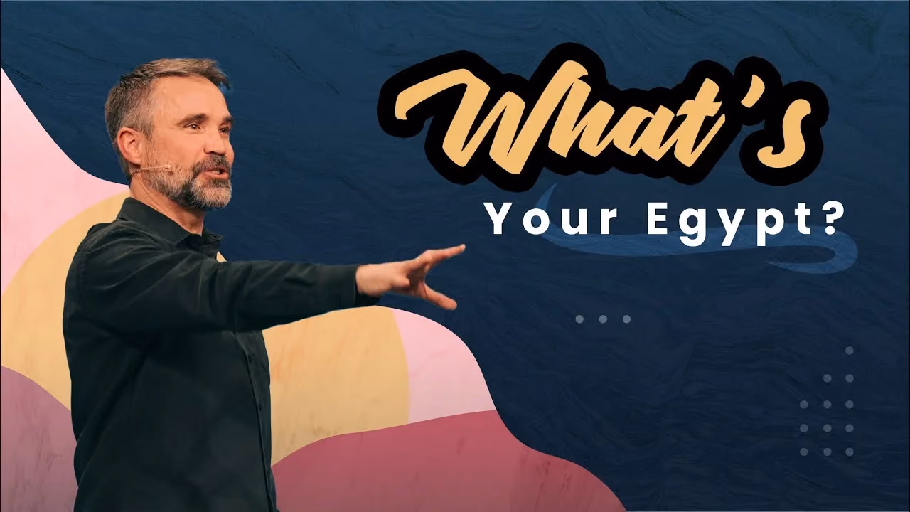 What's Your Egypt? Speaker in a dark jacket pointing while preaching on a pastel-muraled stage.