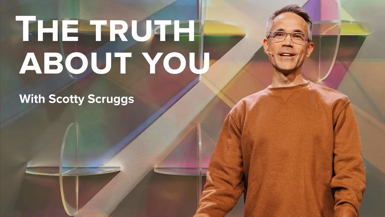 The Truth About You with Scotty Scruggs, in a rust sweatshirt before panels of coloured glass.