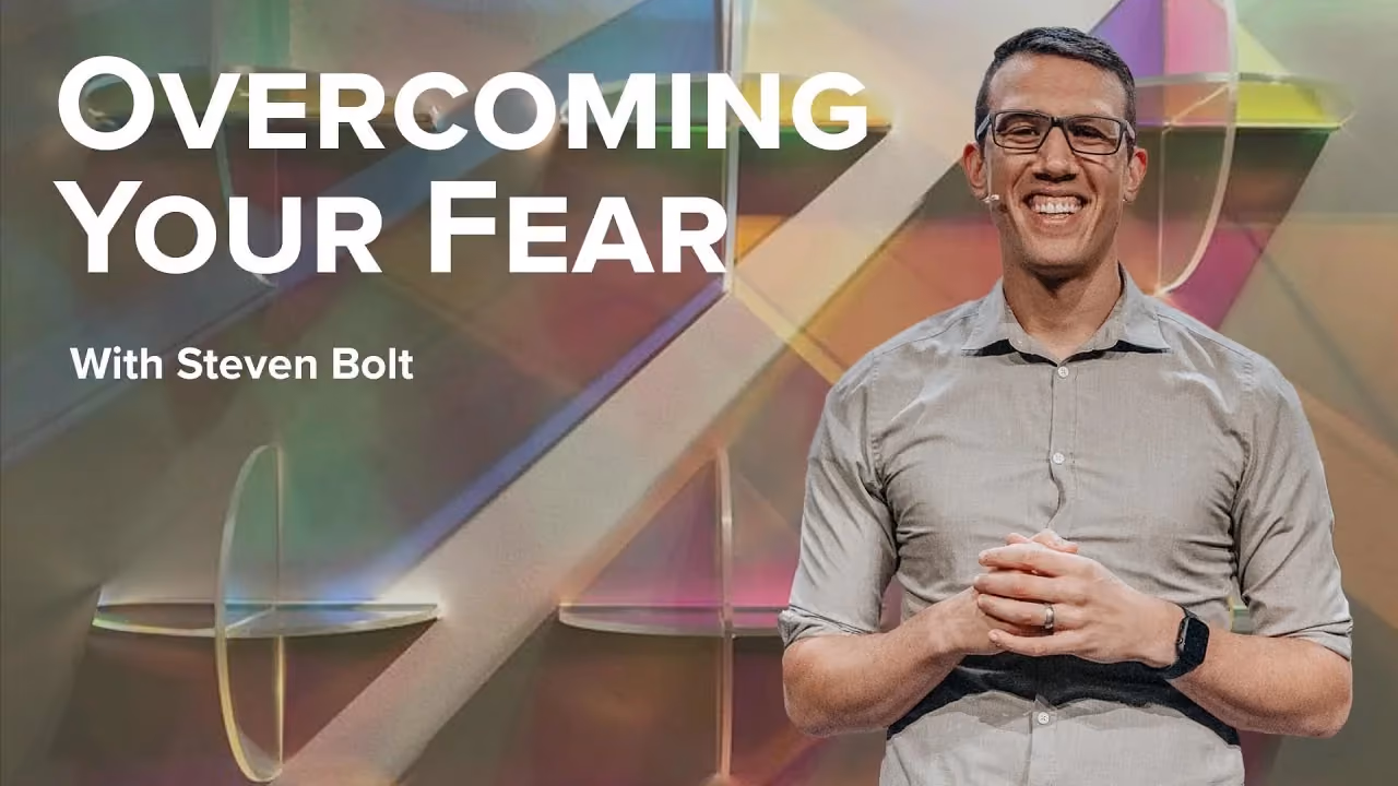 Overcoming Your Fear with Steven Bolt, hands together before panels of coloured glass.