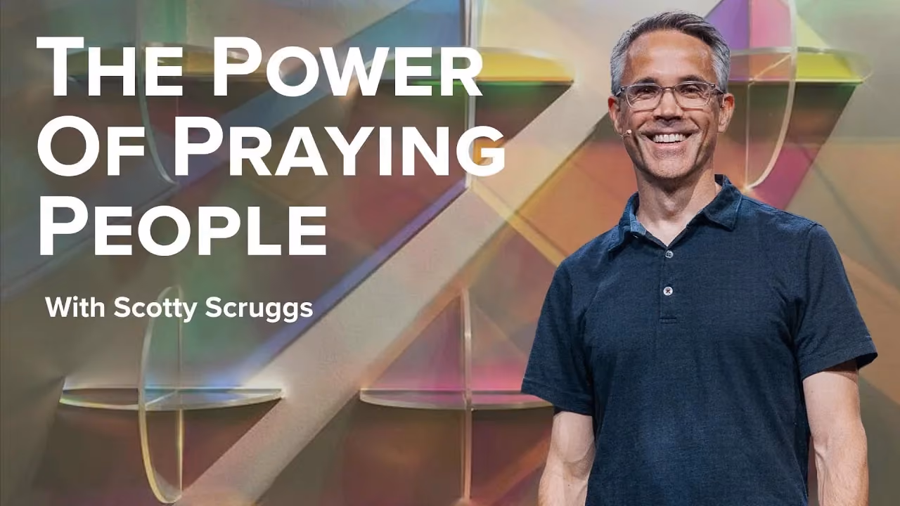 The Power of Praying People with Scotty Scruggs, in a navy polo before coloured glass panels.