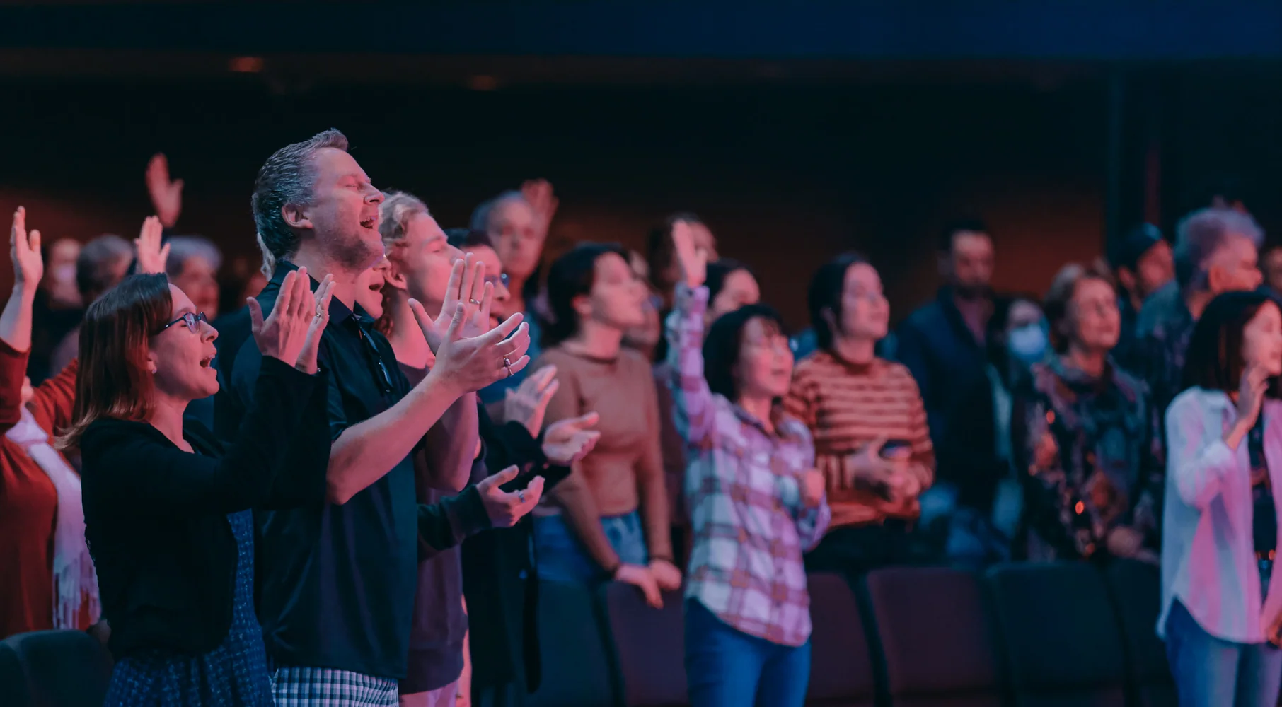 Photo of a church congregation clapping with hands raised during a worship service