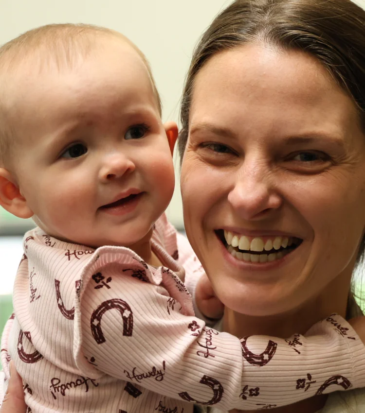 Close-up photo of a smiling mother holding her smiling baby
