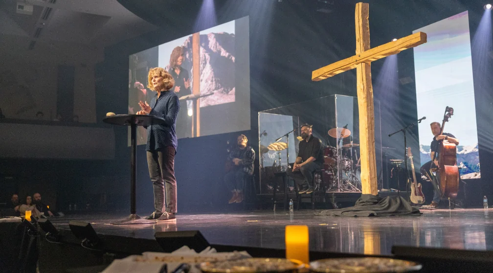 Musicians leading worship in front of a cross during a service.